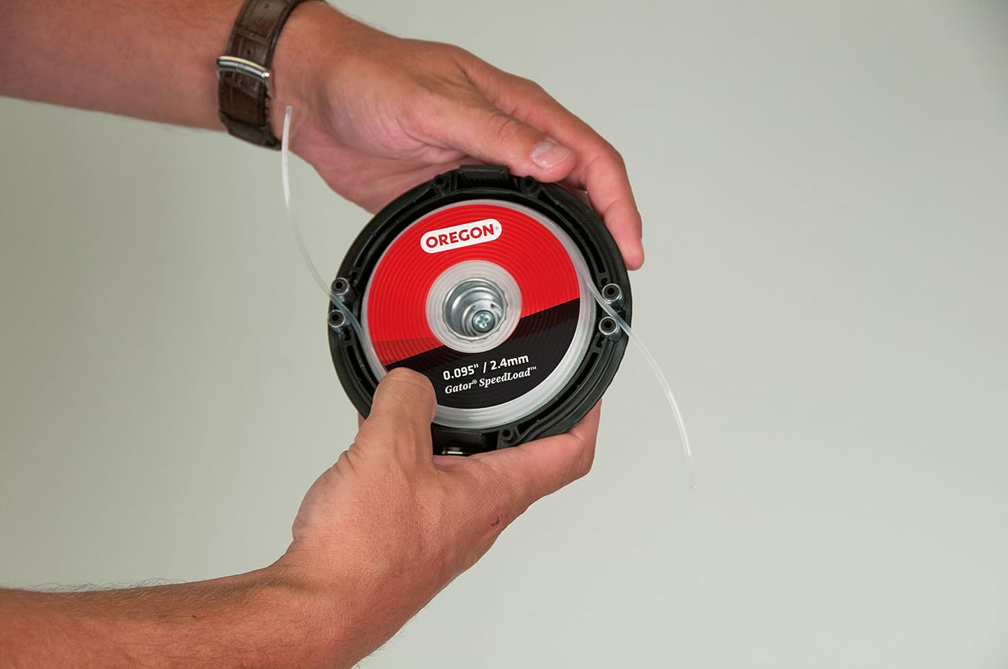 Mani che tengono una testina di ricambio per decespugliatore Oregon Gator SpeedLoad da 0.095 pollici/2.4 mm. Ottima per taglio erba e giardinaggio. Facile da installare e utilizzare, ideale per manutenzione del prato.