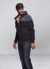 Giacca con cappuccio STIHL nera e grigia con zip, indossata da uomo con cappellino coordinato. Giacca sportiva, casual, perfetta per l'outdoor, con logo STIHL arancione sul petto. Abbigliamento uomo, moda autunnale.