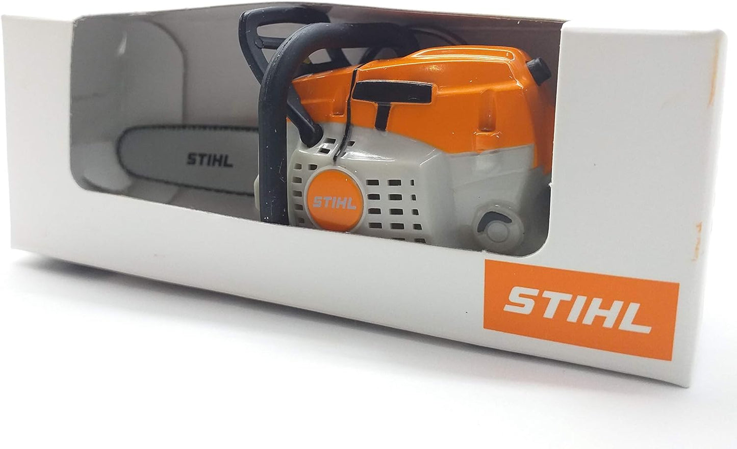 Motosega giocattolo Stihl in confezione bianca con finestra trasparente, motore arancione e logo Stihl visibile. Perfetto per bambini appassionati di attrezzi da giardino e per collezionisti di modellini.