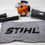 Soffiatore aspiratore a scoppio STIHL SH 86 con motore arancione, tubo di aspirazione e soffiaggio, sacco di raccolta grigio con logo STIHL nero, accessori inclusi. Potente attrezzo da giardino per foglie e detriti.