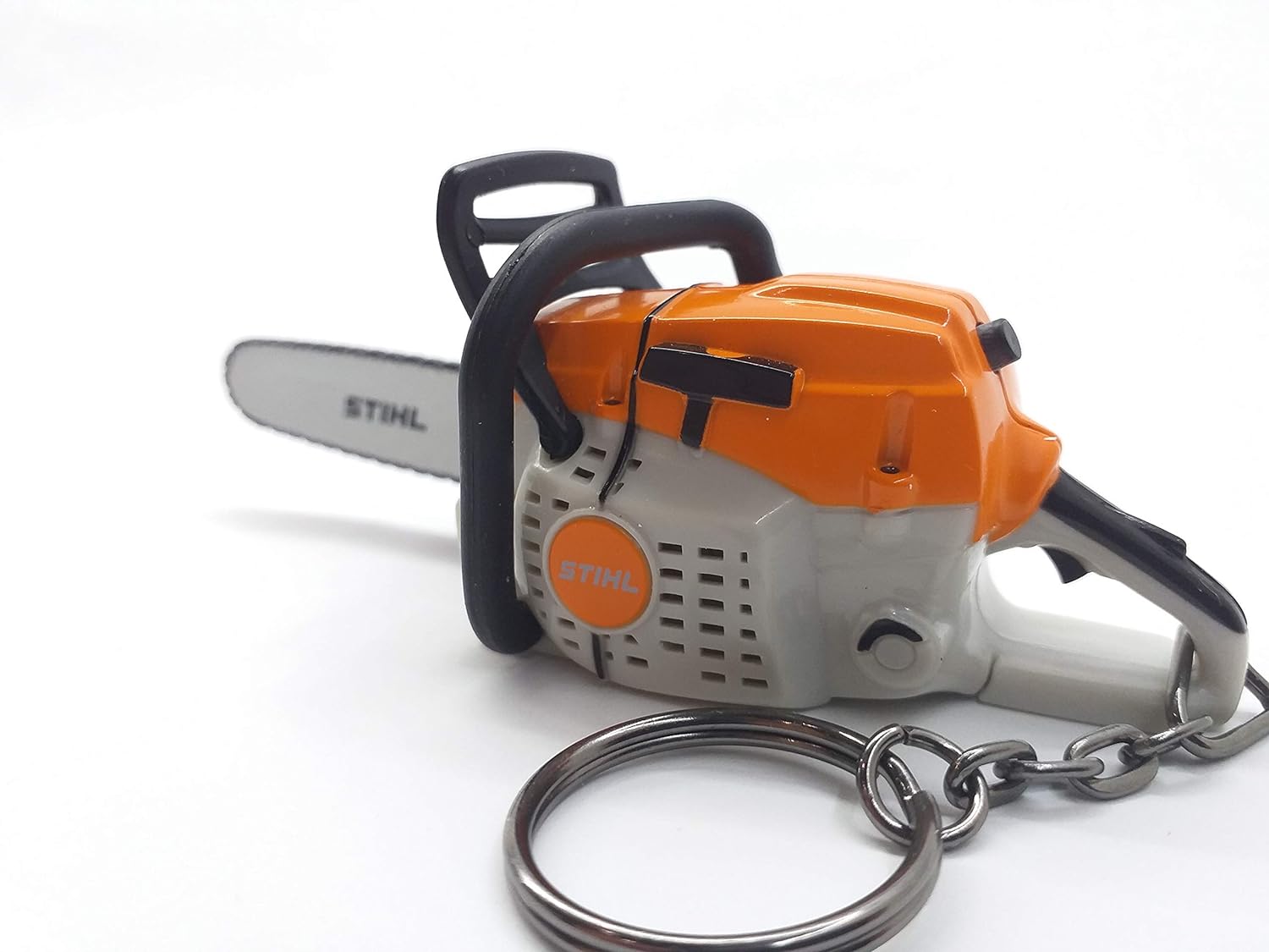 Portachiavi a forma di motosega STIHL, modello in miniatura con dettagli realistici, colore arancione e grigio, accessorio perfetto per appassionati di bricolage e giardinaggio. Gadget originale e utile per tenere le chiavi organizzate.