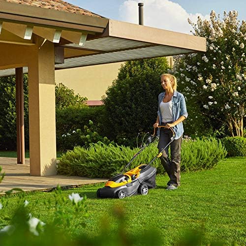 Donna che utilizza un tagliaerba elettrico su un prato verde ben curato vicino a una casa moderna con giardino. Ideale per il giardinaggio domestico, il tagliaerba garantisce un prato perfetto con facilità e comfort. Tagliaerba elettrico, giardinaggio, prato curato.