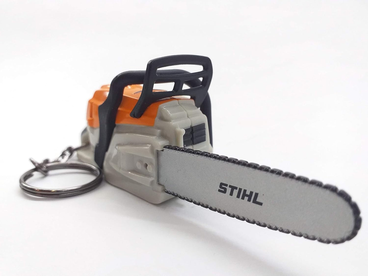 Portachiavi a forma di motosega STIHL, miniatura dettagliata con lama argentata e corpo arancione. Ideale per appassionati di bricolage e giardinaggio, accessorio perfetto per chiavi o zaini. Gadget originale e pratico.