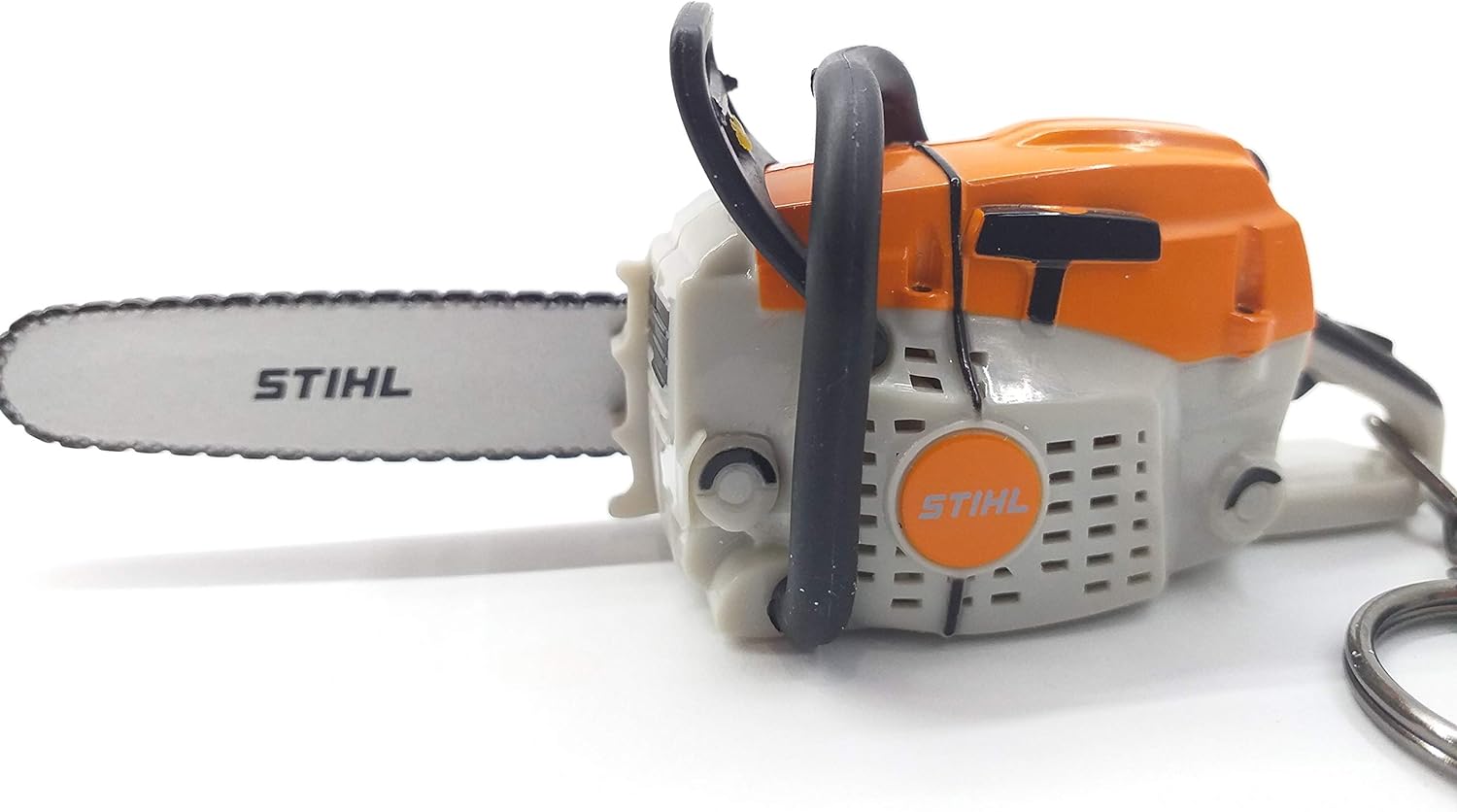 Mini motosega giocattolo Stihl in plastica arancione e grigia con portachiavi. Realistica riproduzione in miniatura con dettagli accurati, ideale come gadget o regalo per appassionati di motoseghe e attrezzi da giardinaggio.