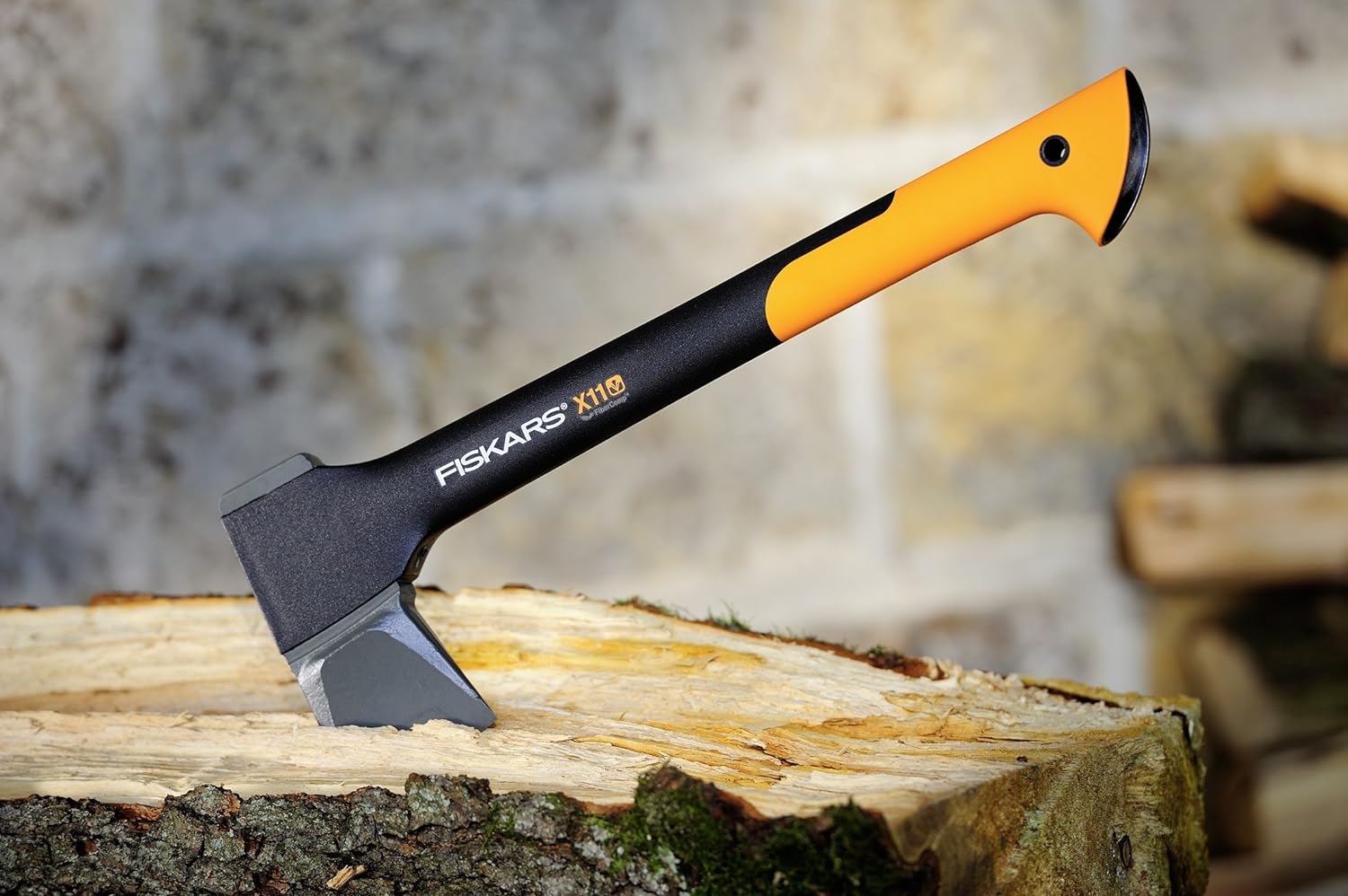 Ascia Fiskars X11 con manico arancione e nero, posizionata su un tronco di legno. Ideale per spaccare legna e attività all'aperto. Design ergonomico e resistente. Strumento perfetto per giardinaggio e lavori forestali.