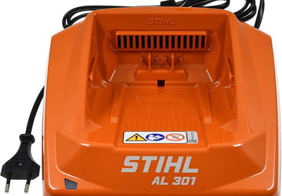 Caricabatterie STIHL AL 301 per attrezzi da giardinaggio, colore arancione, con cavo di alimentazione e spina a due poli. Compatibile con batterie agli ioni di litio. Design robusto e indicazioni di sicurezza visibili.