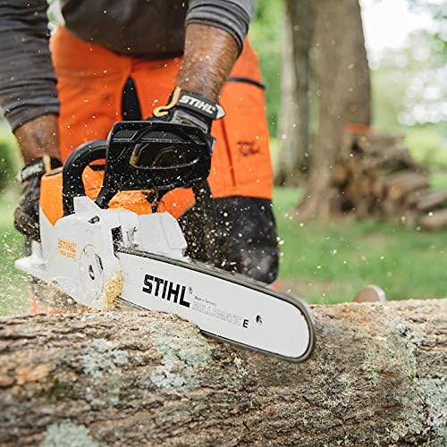 Operaio utilizza motosega STIHL per tagliare tronco di legno in giardino. Indossa guanti e pantaloni di sicurezza arancioni. L'attrezzo è in azione, con trucioli di legno che volano. Ambiente esterno con alberi e legna accatastata sullo sfondo.