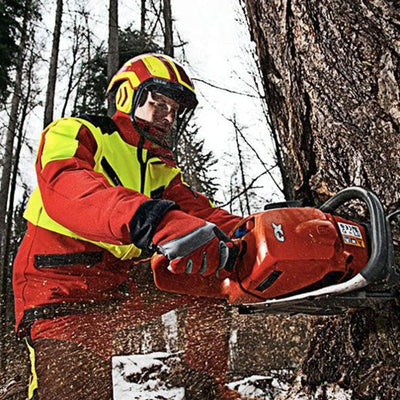 Boscaiolo con abbigliamento protettivo rosso e giallo utilizza una motosega arancione per tagliare un albero in una foresta innevata. Equipaggiamento di sicurezza per lavori forestali, protezione personale e attrezzature professionali per il taglio del legno.